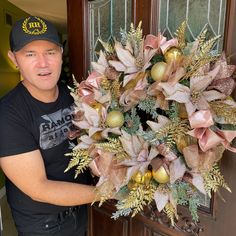 a man standing next to a door holding a wreath with christmas decorations on it and an ornament hanging from the front