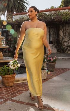 a woman in a yellow dress walking down the street