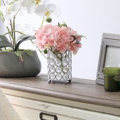 a vase filled with pink flowers sitting on top of a dresser