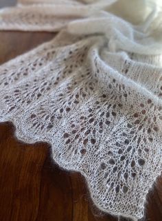 a white shawl is sitting on top of a wooden table and it looks like something out of an old book