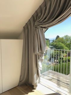 an open window with drapes and curtains on the outside, looking out onto a balcony