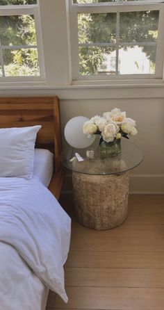 a bedroom with a bed, table and two vases on the floor next to each other