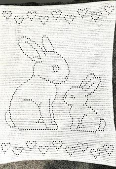 a white crocheted blanket with an image of a rabbit on it's back