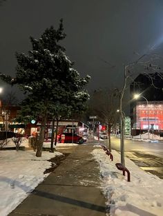 the street is covered in snow and has no cars parked on it at night time