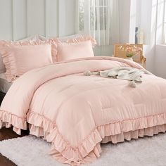 a pink comforter with ruffles and pillows on a white rug in a bedroom