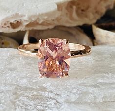 a pink diamond ring sitting on top of a rock