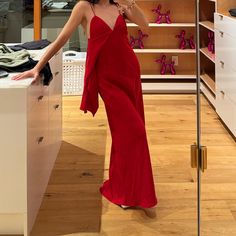 a woman in a red dress standing next to a dresser