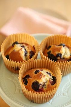 four blueberry muffins sitting on a plate