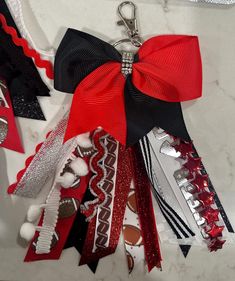 a red, black and white ribbon with footballs on it is attached to a keychain