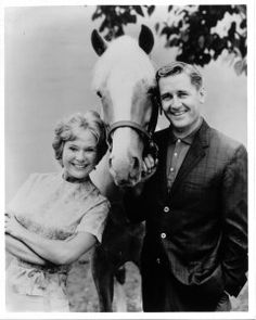 a man and woman standing next to a horse