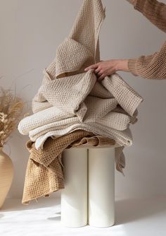 two women are holding up some cloths on top of each other in front of a vase