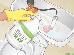 a person in yellow gloves is cleaning a white sink with a green and red spray bottle