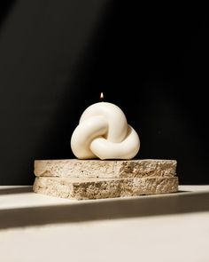 a white candle sitting on top of a stone block