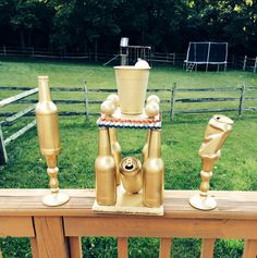 gold candlesticks are placed on top of a wooden fence