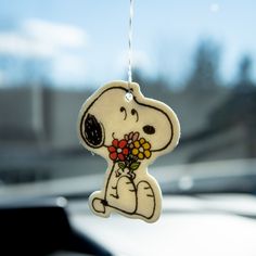 a small snoopy with flowers hanging from it's back end on a string