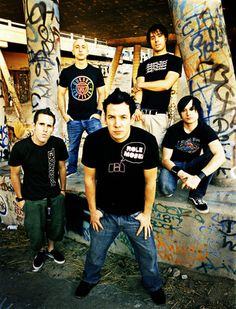 a group of young men standing next to each other in front of graffiti covered walls