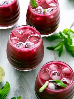 three glasses filled with red liquid and garnished with mint