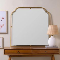 a mirror sitting on top of a wooden table next to a lamp