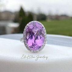 an oval shaped amethorate and diamond ring on top of a white table