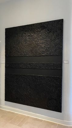 a large black piece of art on the wall in a room with tile flooring