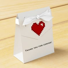 a small white bag with a red heart on it that says thank you for coming