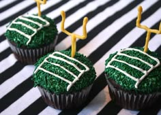 three cupcakes with green frosting and white icing on a black and white striped tablecloth