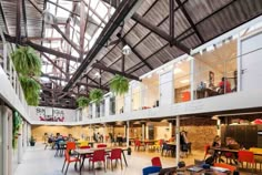 the inside of a building with tables, chairs and plants hanging from it's ceiling