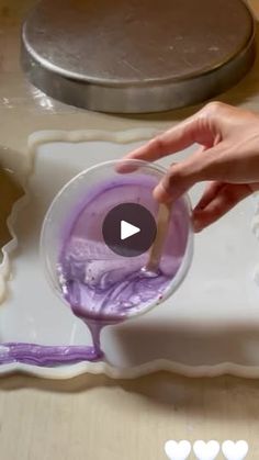 a person is mixing purple liquid in a bowl on a tray with other items around it