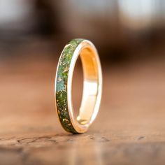 Presenting The Erinn - a beautiful gold women's wedding band made of 100% recycled gold and a captivating center inlay of green imperial diopside and gold flakes. Inspired by the emerald landscapes of Ireland, this ring is perfect for the bride who wants a piece of jewelry that is both timeless and unique.The Erinn Ring Features: SCS certified 100% recycled gold ring base Available in: 10K, 14K or 18K yellow gold, rose gold or white gold Natural imperial diopside ring inlay with gold flakes Hand Recycled Gold Ring, Engraving Fonts, 10k Gold Ring, Gold Mining, Gold Flakes, Womens Wedding Bands, 14k Gold Ring, Recycled Gold, Gold Wedding Band