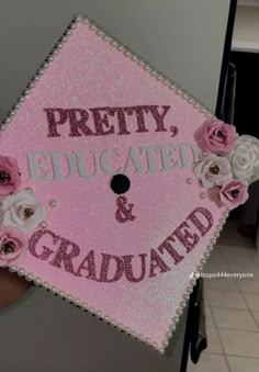 a pink graduation cap that says pretty, educated and gradulated with flowers