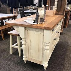 a kitchen island made out of an old white cabinet with wood top and two stools