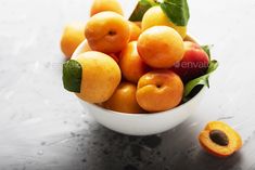 a white bowl filled with lots of fruit on top of a metal table next to a sliced peach