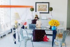 a woman sitting at a table with a laptop computer in front of her and yellow flowers