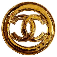 A lovely and large Chanel brooch from the 1994 spring collection. It measures 2.5 inches in diameter. The cutout Chanel CC logo is lightly domed within its .38 of an inch border. Additionally, the brooch has a light Martele' or hammered texture on the front and back. The 18K gold plate has a rich gold color. On the bottom and back is the Chanel oval signature plaque inscribed with copyright and registry marks, CHANEL, 94 (1994), CC in a circle logo, P (Printemps/Spring) and 'Made in France.' There is a small scratch on this signature plaque. Otherwise, the brooch is in very very fine to excellent condition. Broche Chanel, Chanel 1994, Logo P, Chanel Brooch, Circle Logo, Circle Logos, Color Dorado, Cc Logo, Vintage Chanel