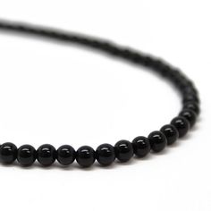 Black Onyx beads are hand strung to form this classic single strand necklace.  The beads are small measuring about 4.0mm.  This is a beautiful, classic black onyx bead necklace.  You could wear this alone or stack with other necklaces for a layering effect.  • 4mm round black Onyx beads• 925 Sterling silver or 14/20 Gold FIlled clasp and ring • Available in 14" to 35" lengthsI have hand strung these beads using a premium beading wire that has beautiful drape and it fastens with a sterling silver Minimalist Black Gemstone Beaded Necklaces, Minimalist Black Beaded Necklace With Gemstones, Black Onyx Round Bead Necklace, Black Minimalist Necklace With Gemstone Beads, Minimalist Black Gemstone Beads Necklace, Black Single Strand Necklace, Onyx Gemstone Beaded Necklaces, Hand-strung Onyx Beaded Necklaces With Round Beads, Classic Black Necklaces With 8mm Beads