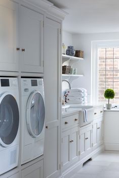 a washer and dryer in a white laundry room with lots of cabinet space