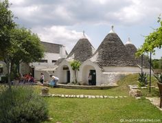 a group of people standing in front of an old building with thatched roof tops