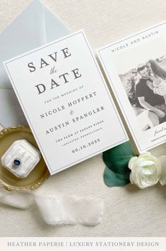 the wedding stationery is laid out on top of an envelope and some white flowers