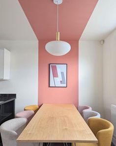 a dining room with pink walls and yellow chairs