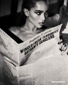 a woman reading a newspaper while laying in bed