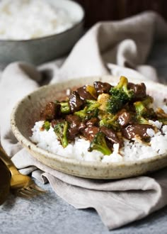 a white bowl filled with rice and broccoli on top of a blue table cloth