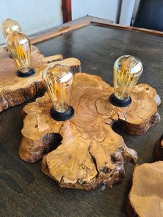 three light bulbs sitting on top of a wooden table next to other pieces of wood