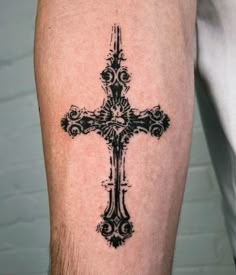 a black and white cross tattoo on the right calf leg, with an intricate design