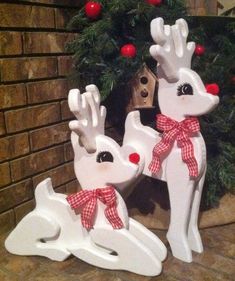 two white reindeer statues sitting next to a christmas wreath