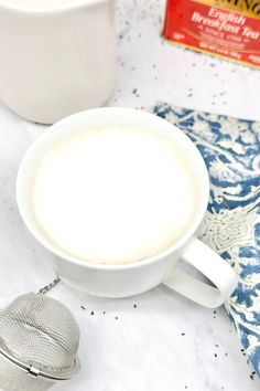 a cup of coffee sitting on top of a table next to a tea strainer