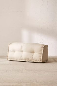 a white couch sitting on top of a wooden floor next to a wall and window