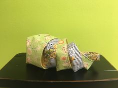 three bags sitting on top of a black table next to a green wall with flowers