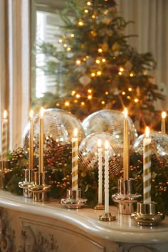 a christmas tree is in the background with disco balls and candles on a mantel