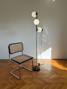 a chair sitting on top of a hard wood floor next to a light pole with three lamps