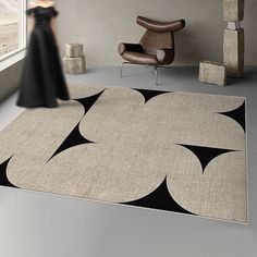 a large rug with black and white shapes on it in a room next to a chair